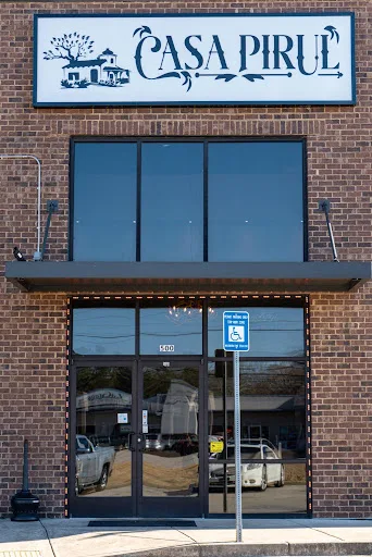 The Casa Pirul storefront in LaGrange, with the blue-lettered sign and house-and-tree logo above the glass entrance of a brick building