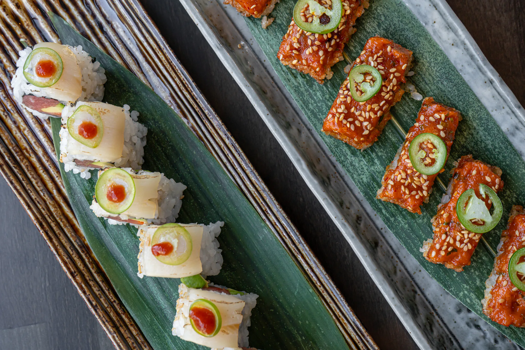 Chef-selected sushi rolls plated on bamboo leaves, finished with sesame, jalapeño and chili sauce at Tomo Japanese in Buckhead